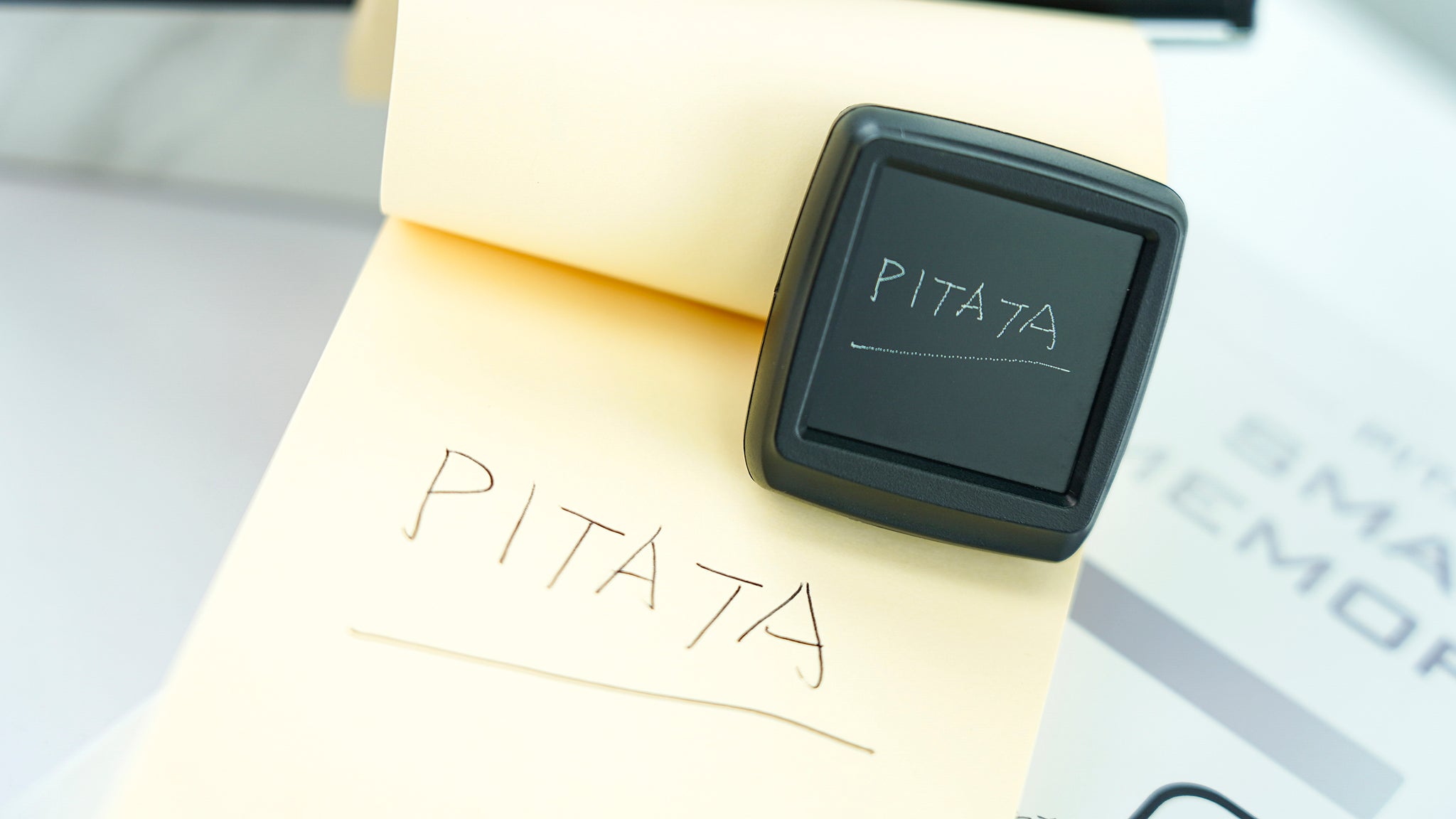 A real PITATA Palm Peeker displaying the same handwritten impression as the memo pad